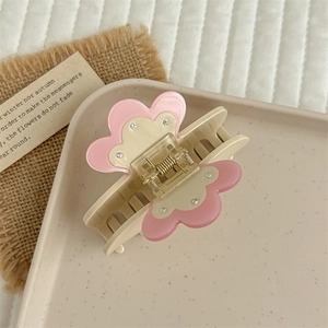 Detail shot of a floral acetate hair claw clip with rhinestones and cream pink finish