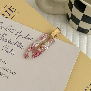 Dettaglio di un fermaglio per capelli in resina trasparente con glitter a stella rosa e oro