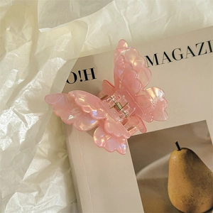 Detail of pink pearlescent butterfly hair claw clip clipped on a magazine page