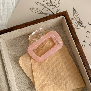 Dettaglio del fermaglio per capelli in acetato rosa marmo con design rettangolare