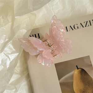 Detail of pink pearlescent butterfly hair claw clip with glossy finish on magazine background