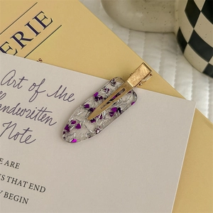 Dettaglio di un fermaglio trasparente con paillettes a cuore viola su carta d'arte