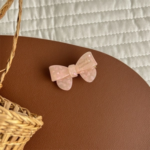 Close-up of pink acetate bow hair clip with gold France Handmade lettering details