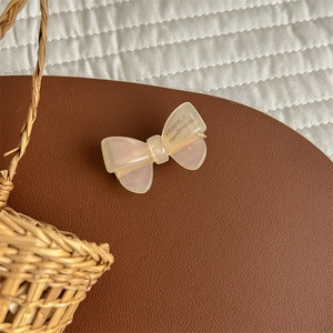 Detail of handmade cream acetate bow hair clip with translucent matte finish and texture