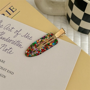 Dettaglio di un fermaglio per capelli in resina con paillettes a stella colorate e clip
