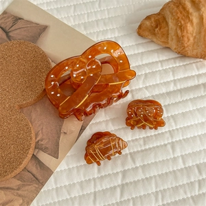 Amber acetate hair claw set featuring pretzel and croissant shapes on white background