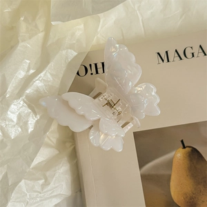 Detail of pearlescent butterfly hair claw clip with golden metal spring on magazine