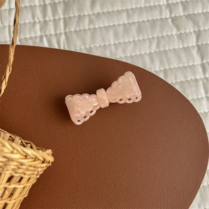 Close-up of pink acetate bow hair clip with elegant pearlescent texture and wavy edges