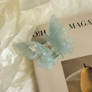 Detail of blue iridescent butterfly hair claw clip clipped on a magazine page