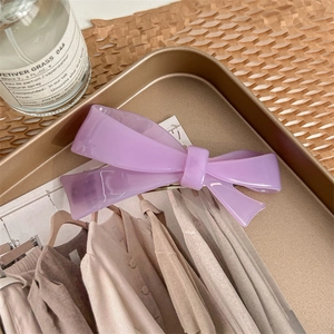Vue détaillée d'une barrette à nœud lilas en acétate posée sur un plateau en bronze rétro