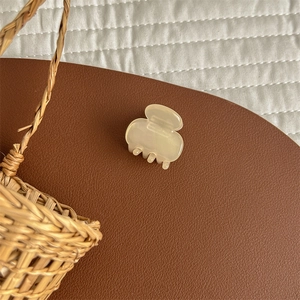 Detail of a creamy jelly translucent acetate hair clip on a brown leather surface