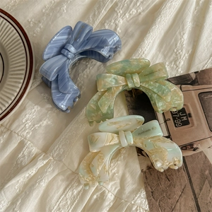 Three acetate bow hair clips in marble patterns of blue, green, and beige handmade style