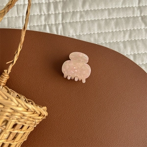 Detailed macro of peach acetate hair clip with marble texture on a quilted background