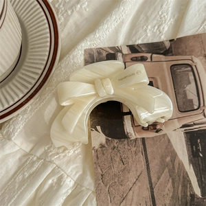 Detailed close-up of handmade cream acetic acid bow hair claw clip with vintage styling