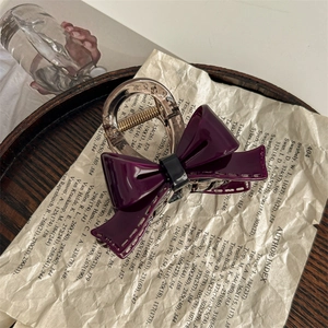 Macro view of dark purple acetate bow hair claw clip with golden metal spring detail