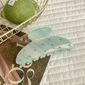 Détail de la pince à cheveux en acétate vert clair avec motifs floraux en strass bleus