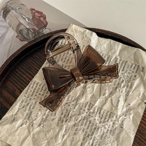 Macro detail of a brown acetate bow hair claw clip on vintage book pages background