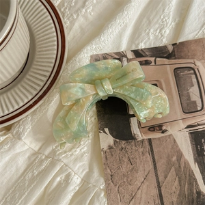Detailed close-up of handmade green acetate bow hair claw clip with marble texture