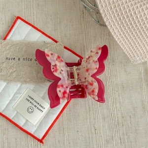 Detail of a dark pink butterfly hair claw with floral marble texture and metal spring