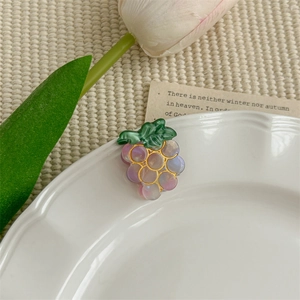 Détail d'une pince à cheveux raisin violet sur assiette en céramique avec une tulipe