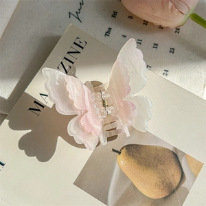 Détail d'une pince à cheveux papillon en marbre rose sur fond de magazine style français