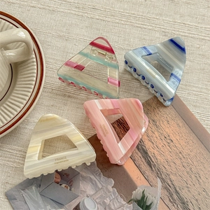 Elegant triangular acetate hair claws in four marble patterns on linen background