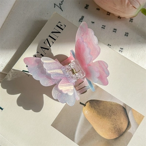 Détail d'une pince à cheveux papillon rose irisé avec finition pailletée et ressort en métal