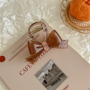 Close-up of coffee brown acrylic bow hair claw clip with detailed stitching and soft textures