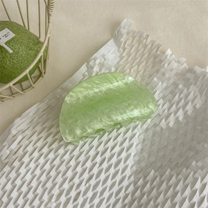 Dettaglio molletta per capelli verde menta con trama marmorea su sfondo bianco