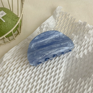 Vista dettagliata della molletta per capelli blu effetto marmo in acetato su carta a nido d'ape