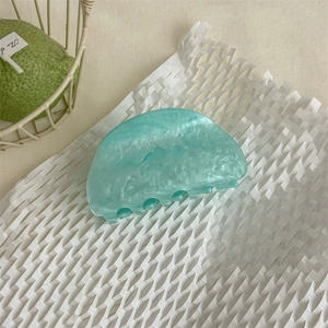 Dettaglio della pinza per capelli in acetato marmorizzato verde menta su carta