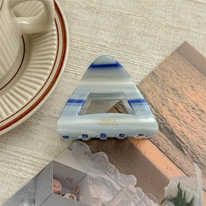 Detailed macro view of acetate hair claw clip with blue stripes and handmade engraving