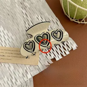 Detail of a beige acetate hair claw clip with black hollow heart pattern decoration