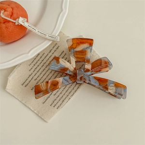 Detail of amber marble hair claw clip with orange and blue acetate texture pattern