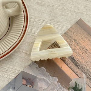 Macro view of triangular acetate hair claw with marble texture and handmade lettering