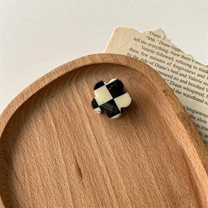 Détail d'une pince à cheveux fleur à damier sur un plateau en bois et papier vintage