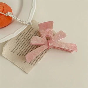 Detailed view of a sweet pink bow hair claw clip with a delicate pearlescent finish