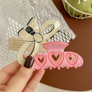 Cream bow and pink hollow heart hair claws set shown in a lifestyle scene for girls