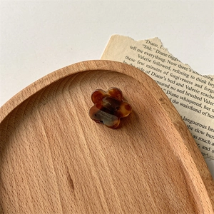 Détail d'une pince à cheveux fleurie en acétate ambré faite main sur bois rustique