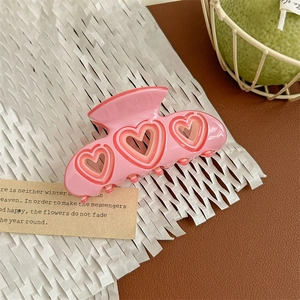 Detailed view of sweet pink heart-shaped acetate hair claw clip with cutout pattern