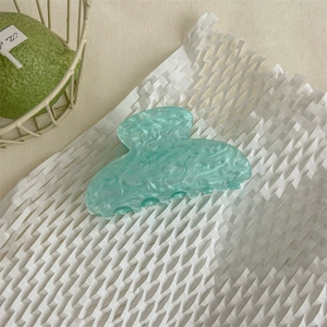 Dettaglio della molletta per capelli in acetato marmorizzato verde menta su carta bianca