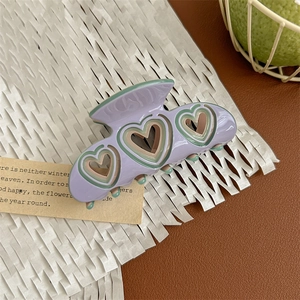 Close-up of heart-shaped hollow acetate hair claw clip with colorful line accents