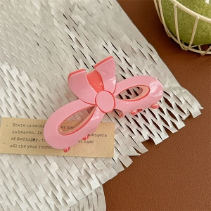 Detail of pink bow-shaped hair claw clip in sweet candy color on decorative paper