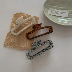 Three rectangular acetate hair claws in marble, tortoiseshell, and dalmatian patterns