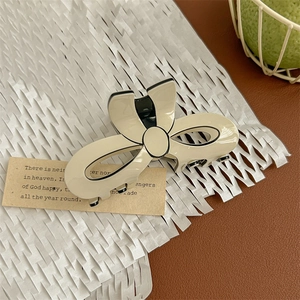 Detail of cream-colored bow hair claw clip with black borders on decorative background
