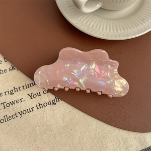 Détail d'une pince à cheveux rose nacré irisé avec un design en forme de nuage ondulé