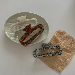 Three elegant acetate shark hair claws with marble and tortoiseshell patterns in a rectangular design