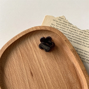 Détail macro d'une pince fleur en acétate écaille avec texte France Handmade sur bois