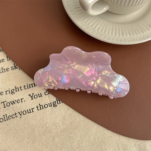 Gros plan d'une pince à cheveux nuage avec fini nacré rose iridescent sur fond en tissu