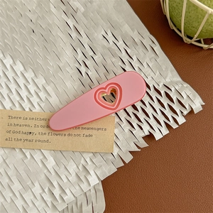 Macro shot of pink heart-shaped cutout on matte finish hair claw clip with bow design